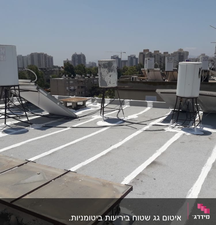 קווים לבנים לאיטום על גג שטוח עם דודי שמש